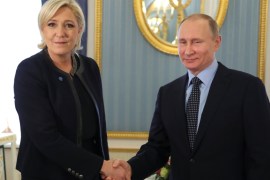 Russian President Putin shakes hands with French far-right party leader Le Pen during their meeting in Moscow