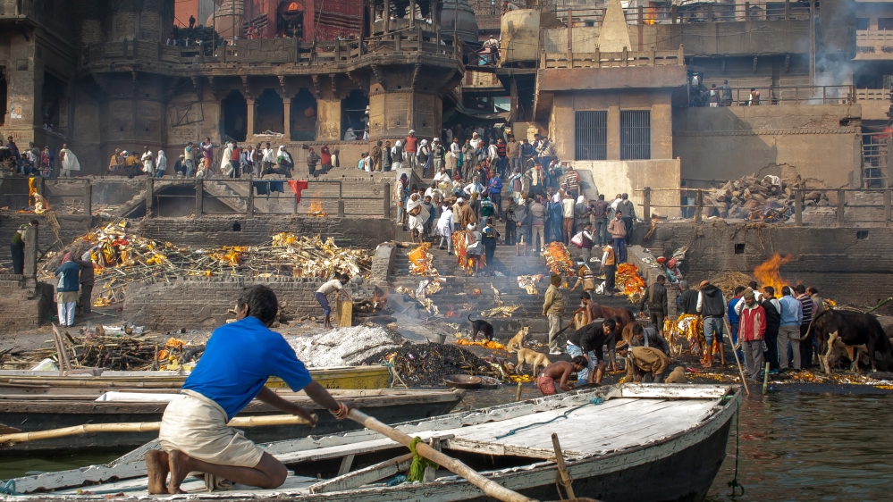 A view of Manikarnika Ghat from the Ganges River. The city is considered a place of sacred crossing from this world to heaven. It is said that when one is cremated in Varanasi, Lord Shiva himself whispers the 'taraka mantra' - the passage mantra - into the ear of the dead. [Radhika Iyengar/Al Jazeera]