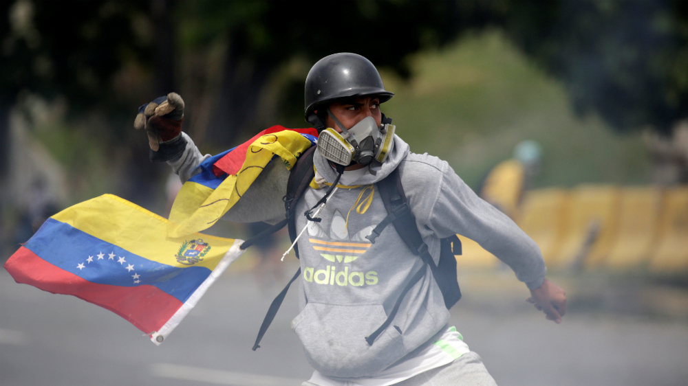 A demonstrator clashes with riot security forces while rallying against Venezuela's President Maduro in Caracas on Wednesday [Marco Bello/Reuters]