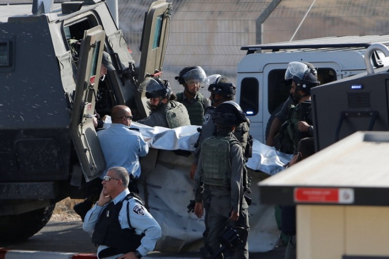 Israeli troops remove the body of a Palestinian who was shot dead after trying to stab Israeli border police at a checkpoint north of the West Bank city of Bethlehem