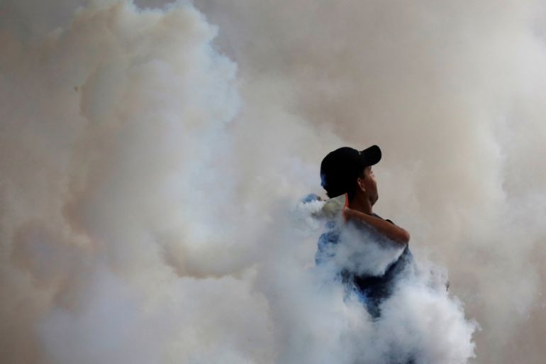 An opposition supporter throws back a tear gas canister during clashes with security forces at a protest against President Nicolas Maduro in Caracas