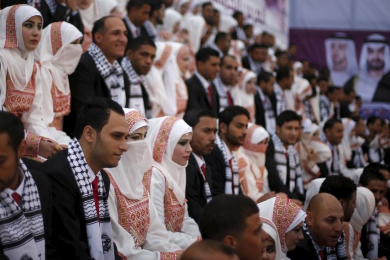 Palestinian grooms sit with their brides on the stage during a mass wedding for 200 couples in Gaza City