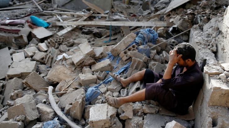 A man sits on the rubble of a house of his relatives, destroyed by a Saudi-led air strike in Sanaa