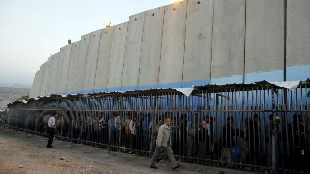 Palestinians wait to cross into Jerusalem next to Israel's controversial Separation Wall at an Israeli military checkpoint in the West Bank town of Bethlehem [Reuters]