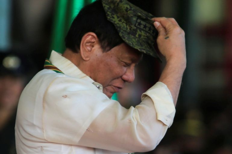Philippine President Rodrigo Duterte tries on a military hat given to him during the 120th founding anniversary of the Philippine Army (PA) at Taguig city, metro Manila