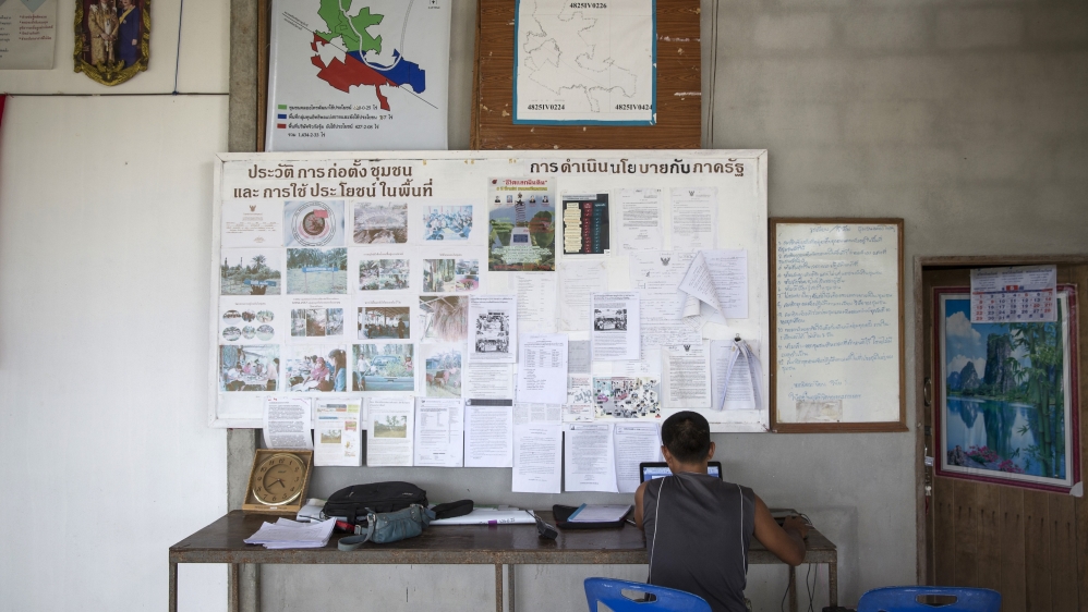 Supot Kalasong works in the communal meeting hall preparing documents to submit to government agencies [Luke Duggleby/Al Jazeera]