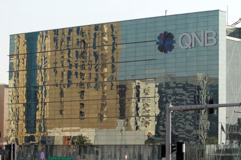 Cars drive past the building of Qatar National Bank (QNB) in Doha