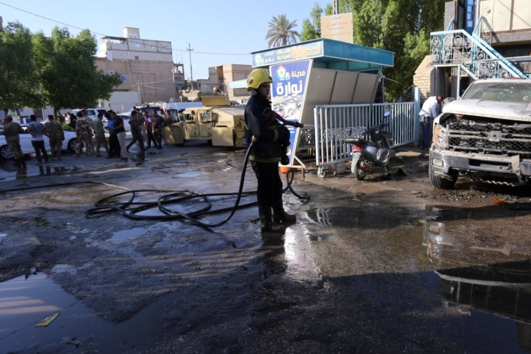 A firefighter hoses down a street after a suicide bomb attack in the city of Kerbala