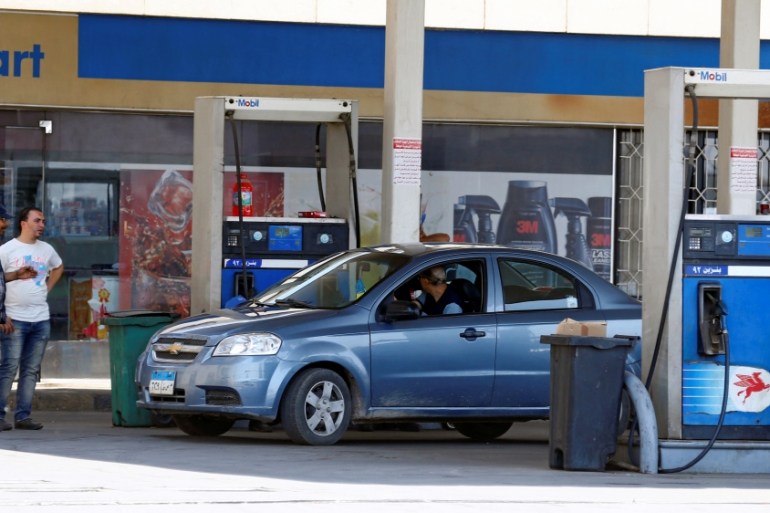 Vehicles are seen being filled up with fuel by employees at a Mobil petrol station in Cairo