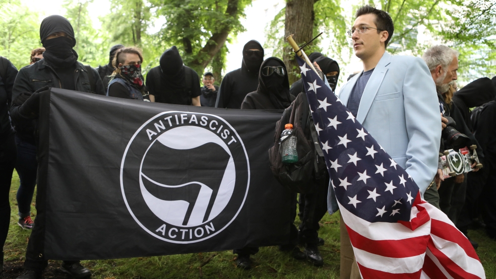 A right-wing protester walks past a group of Antifa activists during an alt-right rally in Portland [Jim Urquhart/Reuters]