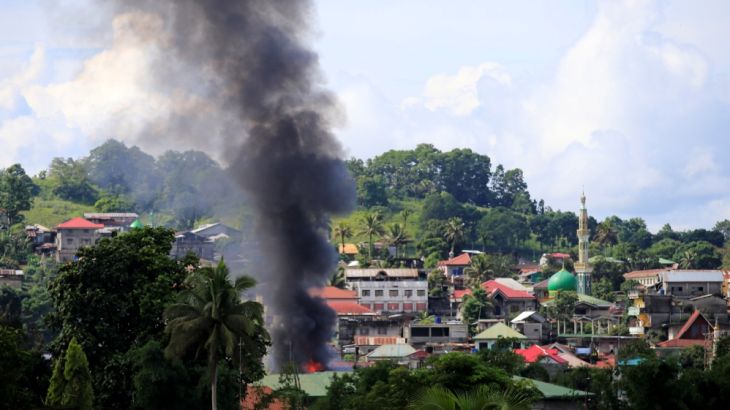 Smoke billowing from a burning building is seen as government troops continue their assault on insurgents from the Maute group, who have taken over large parts of Marawi City