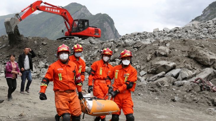 Rescue workers carry a victim at the site of a landslide that occurred in Xinmo Village