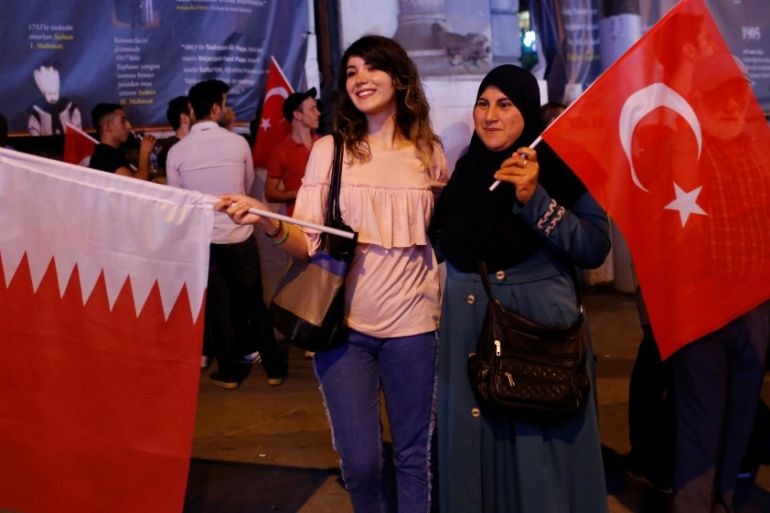 Women pose with Turkish and Qatari flags during a demonstration in favour of Qatar in central Istanbul