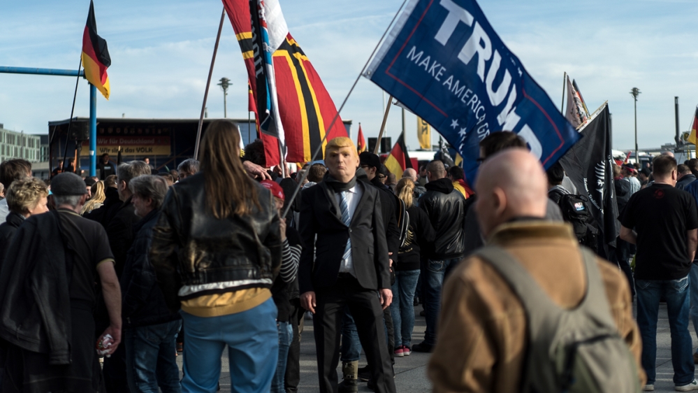 Far-right demonstrators held flags for US President Donald Trump at an anti-refugee rally in Berlin [Sorin Furcoi/Al Jazeera]