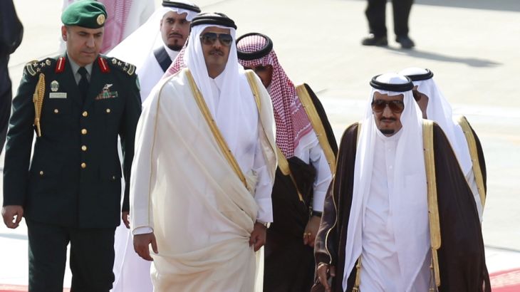 Saudi King Salman bin Abdulaziz walks with the Emir of Qatar