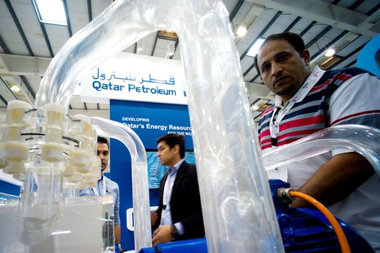 FILE PHOTO: Visitors look at an oil purification unit at the Qatar Petroleum Company booth during a petrochemicals conference in Manama, Bahrain