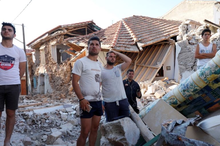 People stand among damaged buildings at the village of Vrissa on the Greek island of Lesbos, Greece, after a strong earthquake shook the eastern Aegean
