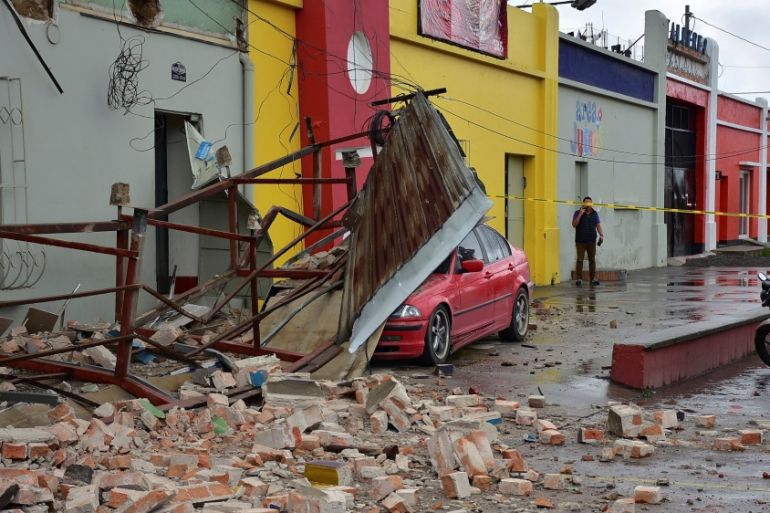 Car covered by debris is seen near a collapsed billboard following an earthquake in Quetzaltenango