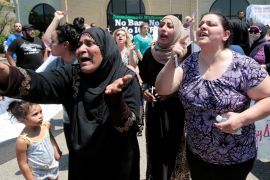 A group of women react as they talk about family members seized on Sunday by Immigration and Customs Enforcement agents during a rally outside the Mother of God Catholic Chaldean church in Southfield