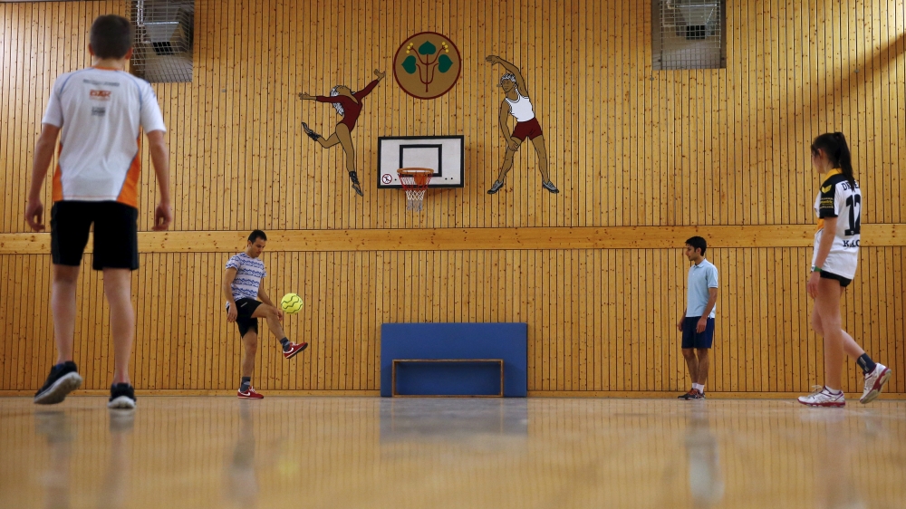 German and refugee teenagers play football in a sports hall in Clausnitz in March 2016 [Hannibal Hanschke/Al Jazeera]