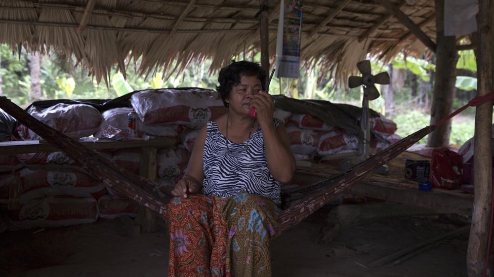 Pratep Pasaja, 54, makes a radio test while being a security guard at one of the posts. Many villagers have walkie-talkies so they can communicate quickly if trouble arises. She will stay in the bunker all night until relieved by another team [Luke Duggleby/Al Jazeera]