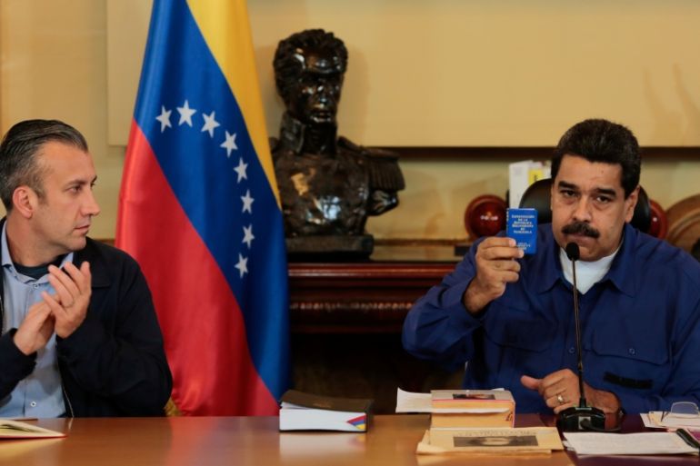 Venezuela''s President Nicolas Maduro shows a copy of the country''s constitution as he sits next to Vice President Tareck El Aissami, during a meeting with Vice Presidents