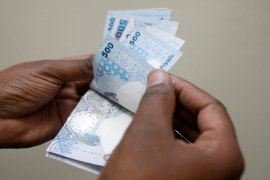 A man counts Qatari riyal notes at a money changer in Doha