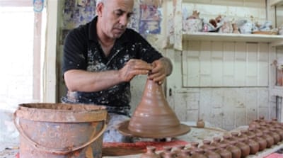 Imad Mohammed uses a potting wheel to create small vessels that will later be glazed and hand-painted, a traditional Hebronite craft [Nigel Wilson/Al Jazeera]