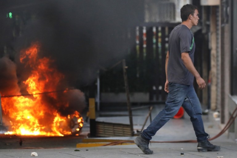 A man walks past a burning barricade after clashes broke out in Caracas