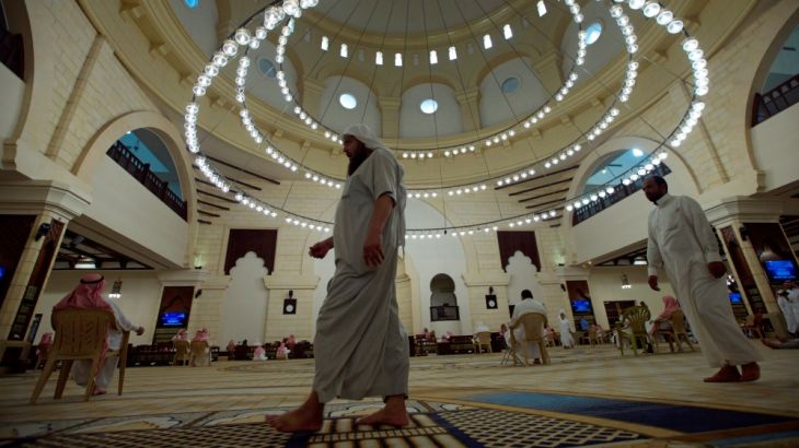 Men walk as others read the Koran in a mosque during the fasting month of Ramadan, in Riyadh