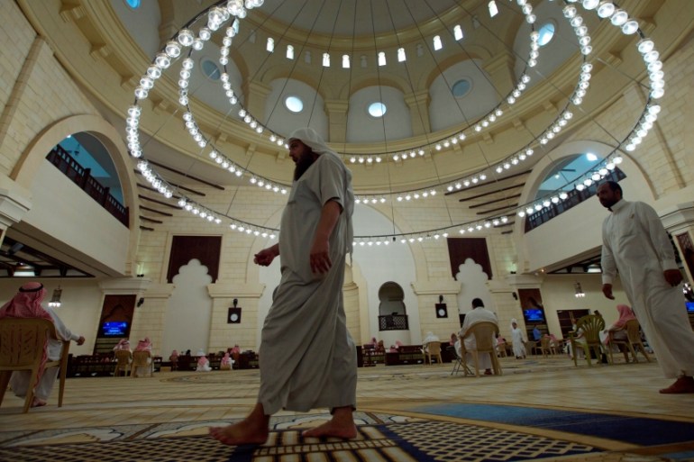 Men walk as others read the Koran in a mosque during the fasting month of Ramadan, in Riyadh