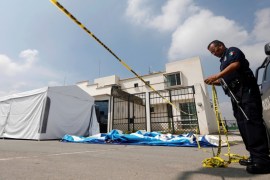 A police officer cordons off a crime scene outside of a house where eleven people were found dead at Villa de los Milagros residential park, in the city of Tizayuca