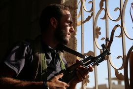 A Free Syrian Army fighter looks out through a window in rebel-held Al-Yadudah village, in Deraa Governorate, Syria