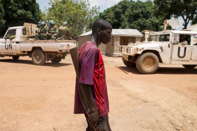 Member of the Anti-Balaka armed militia walks next to United Nations peacekeeping soldiers in the village of Makunzi Wali, Central African Republic