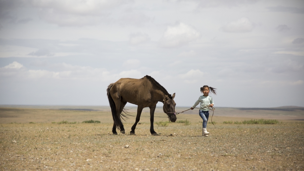 Yanjinlkham Damdinsuren, five, exercises one of her family’s horses as her sister trains for the 24km race the next day. Yanjinlkham hopes to compete next year [Hannah Griffin/Al Jazeera]