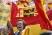 Spain's unionist protesters fly Catalan and Spanish flags during Spain's National Day at Catalonia Square in Barcelona. The banner reads 'Bridges, not walls' [Albert Gea/Reuters]