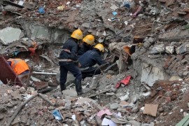 Firefighters remove debris as they search for survivors at the site of a collapsed building in the suburbs of Mumbai