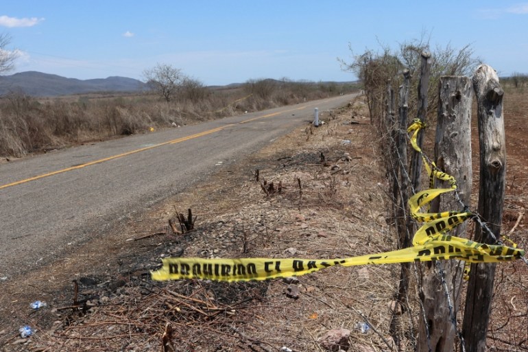 A police cordon tied to barbed-wire fence is seen in an area of a crime scene after people were killed during shootouts between police and gunmen on the road to the town of Aguaje de Costilla, near th