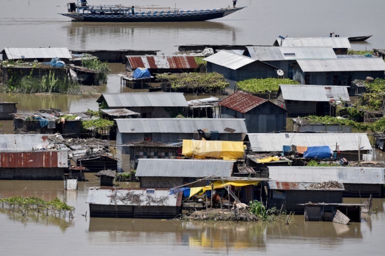 Villagers use a boat as they row past partially submerged houses at a flood-affected village in Morigaon district
