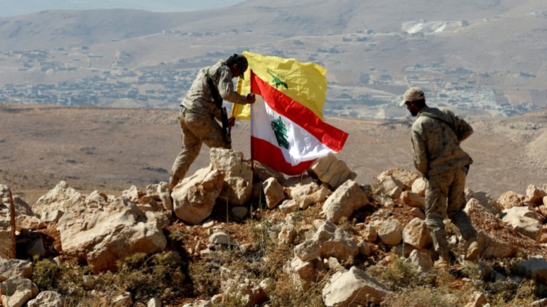 Pejuang Hizbullah memasang bendera Lebanon dan Hizbullah di Juroud Arsal, perbatasan Suriah-Lebanon