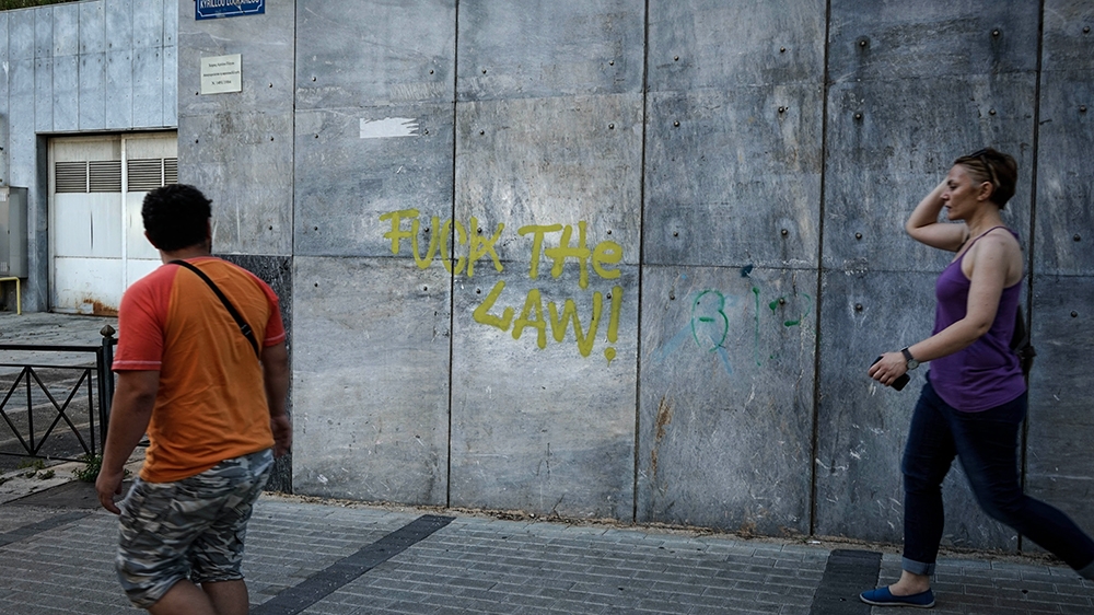 Anti-government graffiti has been spray painted on the side of the Greek Supreme Civil and Criminal Court [Patrick Strickland/Al Jazeera]