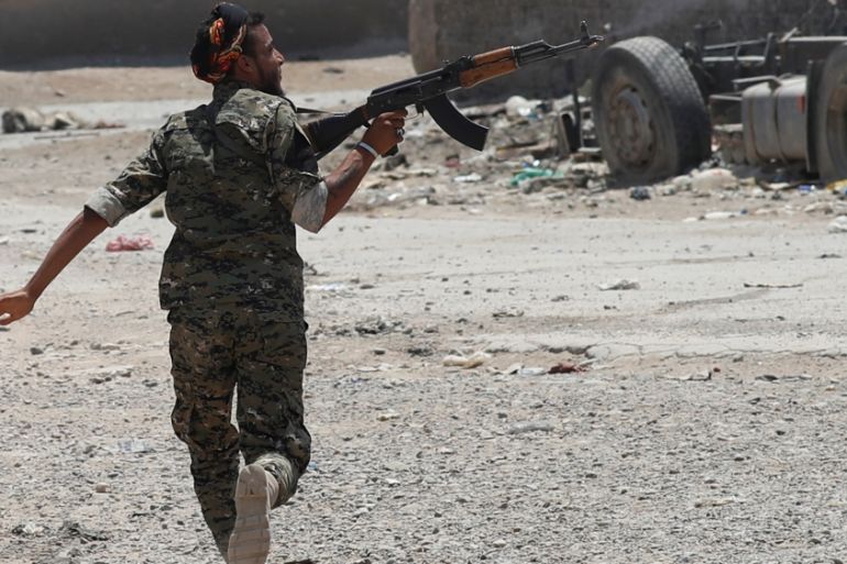 A Kurdish fighter from the People''s Protection Units (YPG) fires his rifle at Islamic State militants as he runs across a street in Raqqa
