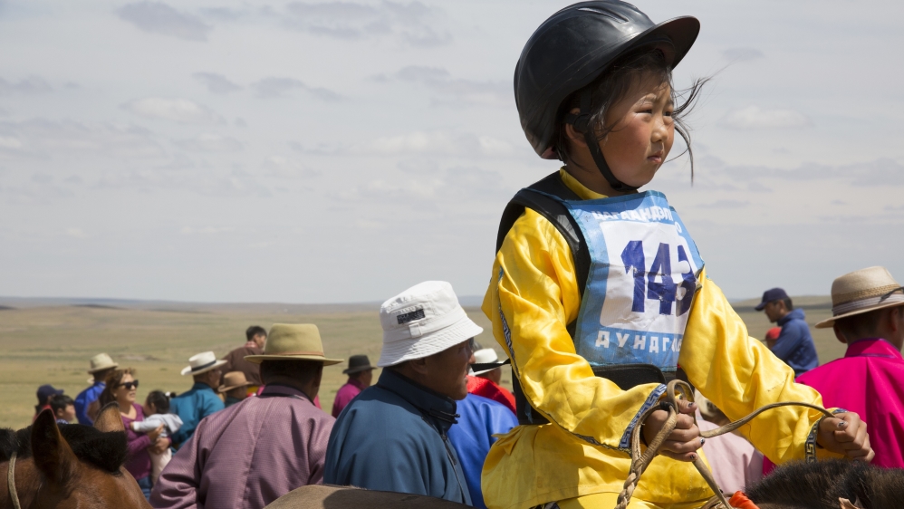 Bujinlkham Damdinsuren awaits the start of the 24km race atop one of her family’s horses at a Naadam festival in Tsagaandelger, Mongolia [Hannah Griffin/Al Jazeera]