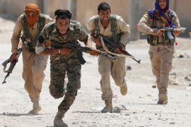 Kurdish fighters from the People''s Protection Units (YPG) run across a street in Raqqa