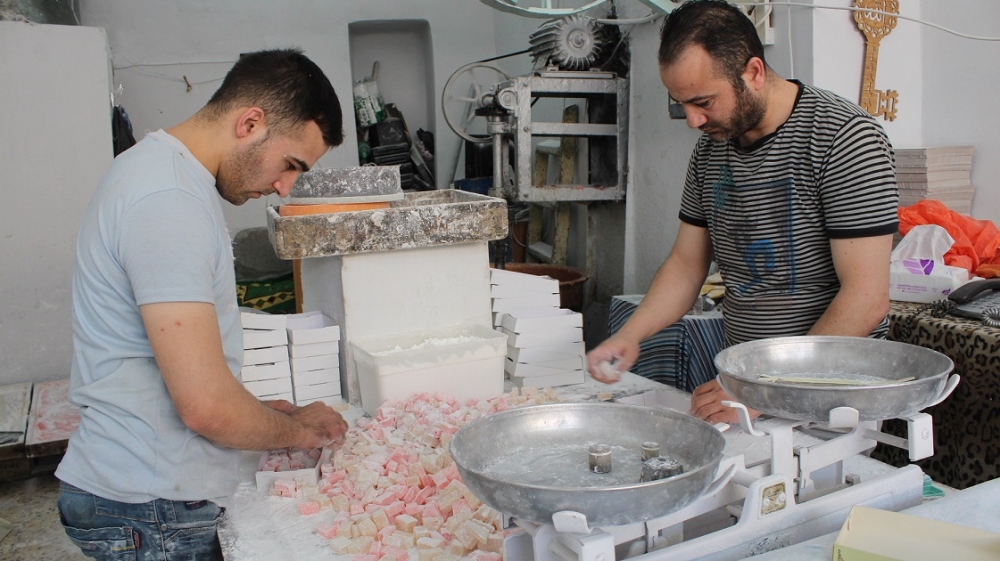 The Old City market is home to makers of traditional food and crafts. Here, two Hebronites prepare boxes of Turkish delight for sale in the market [Nigel Wilson/Al Jazeera]