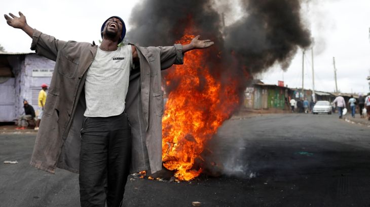 A supporter of opposition leader Raila Odinga gestures in front of burned barricade in Kibera slum in Nairobi