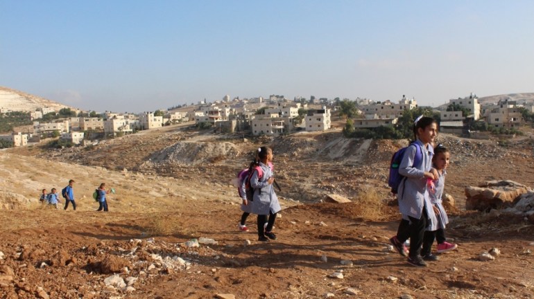 Palestine school children walking over scrubby land to get to their temporary school