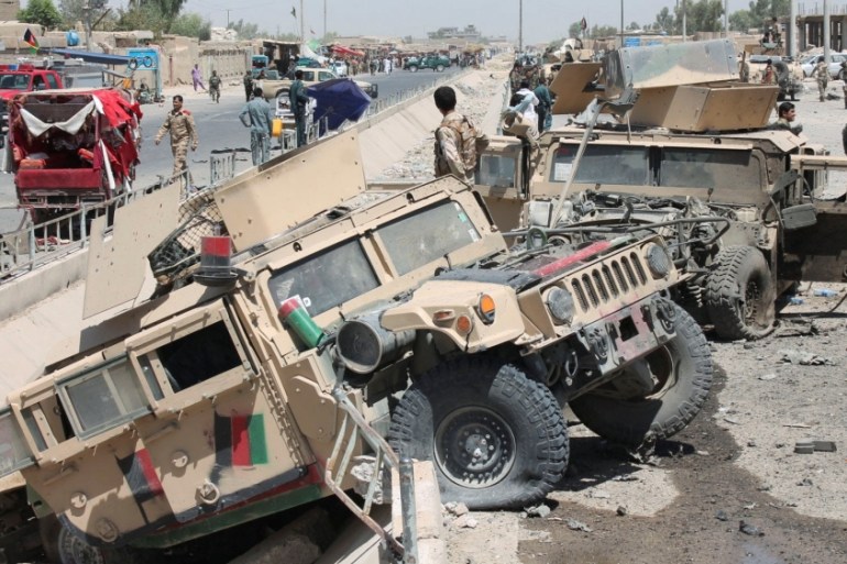 Afghan National Army (ANA) soldiers inspect damaged army vehicles after a suicide attack in Lashkar Gah, Helmand province, Afghanistan