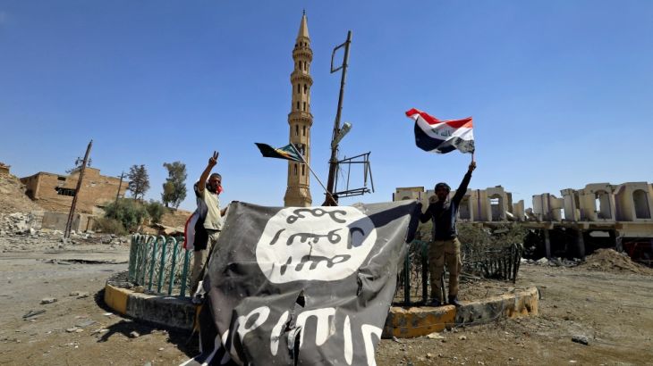 Shi''ite Popular Mobilization Forces (PMF) members hold an Islamic State flag, which they pulled down, during the war between Iraqi army and Shi''ite Popular Mobilization Forces (PMF) against the Islami
