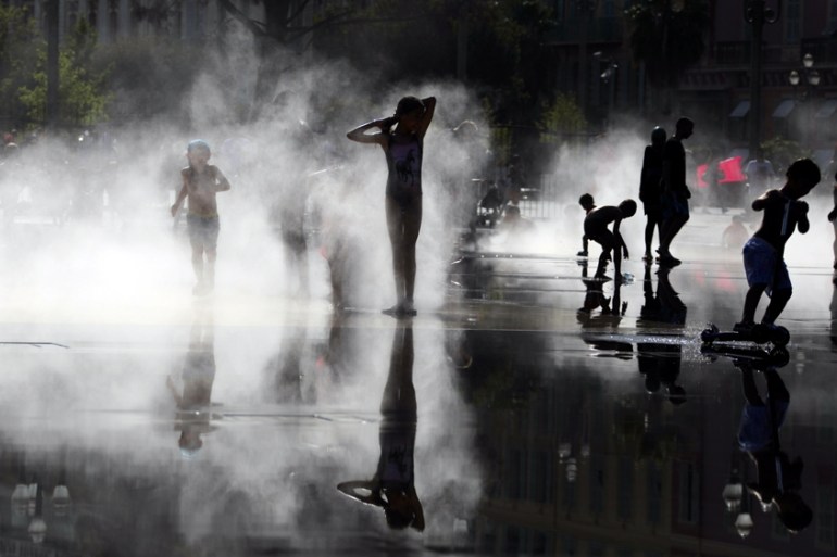 Children play in mist at a water fountain as a heatwave hits south of France in Nice, France August 2, 2017.